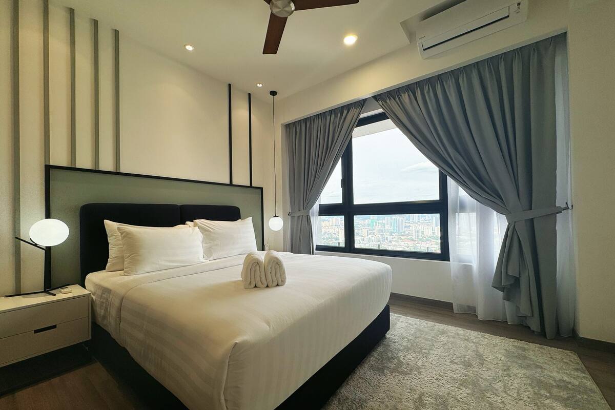 Habitación de hotel moderna con una cama grande, ventilador de techo, aire acondicionado y vista a la ciudad a través de la ventana.