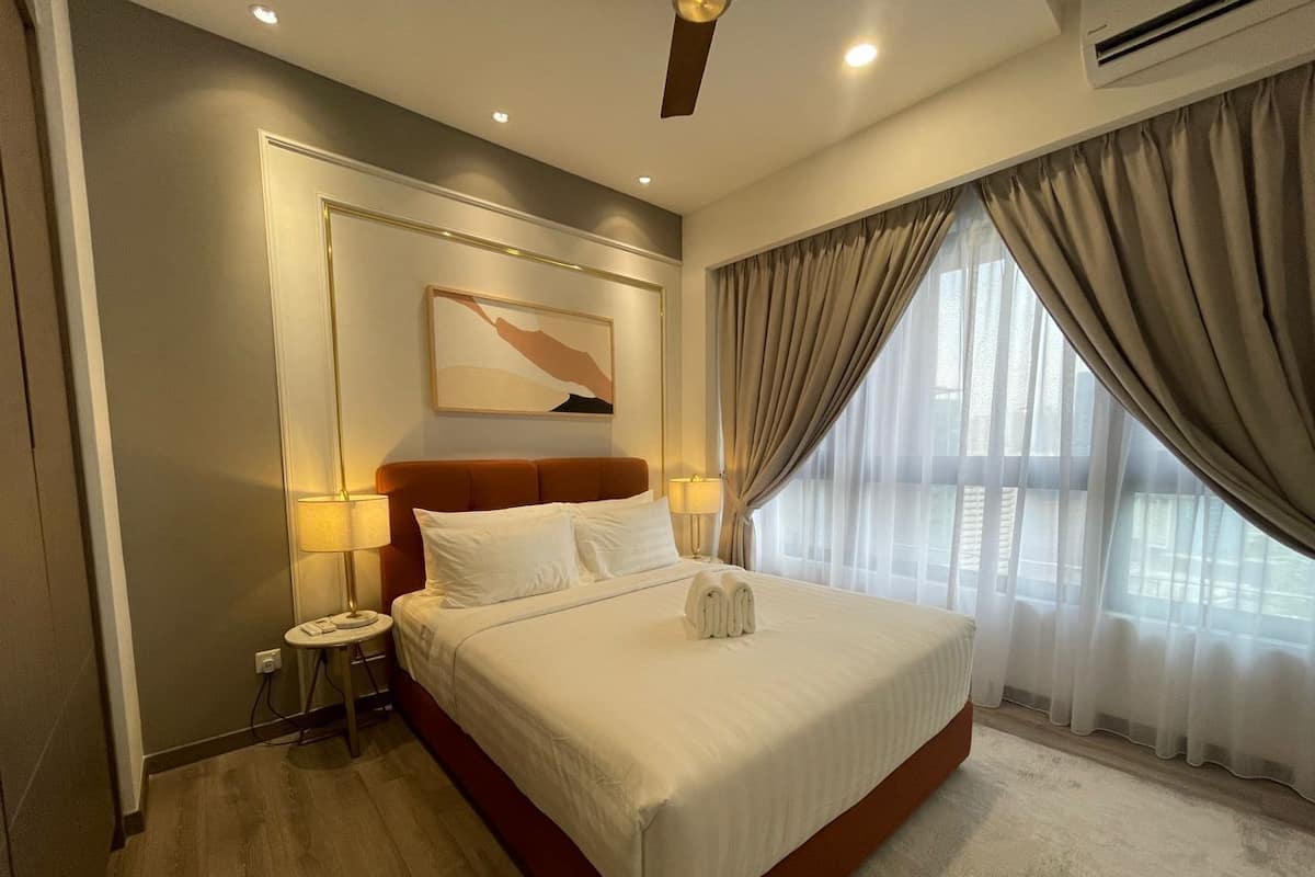 Habitación de hotel con una cama grande, una mesita de noche, una obra de arte colgada en la pared y una ventana con cortinas.