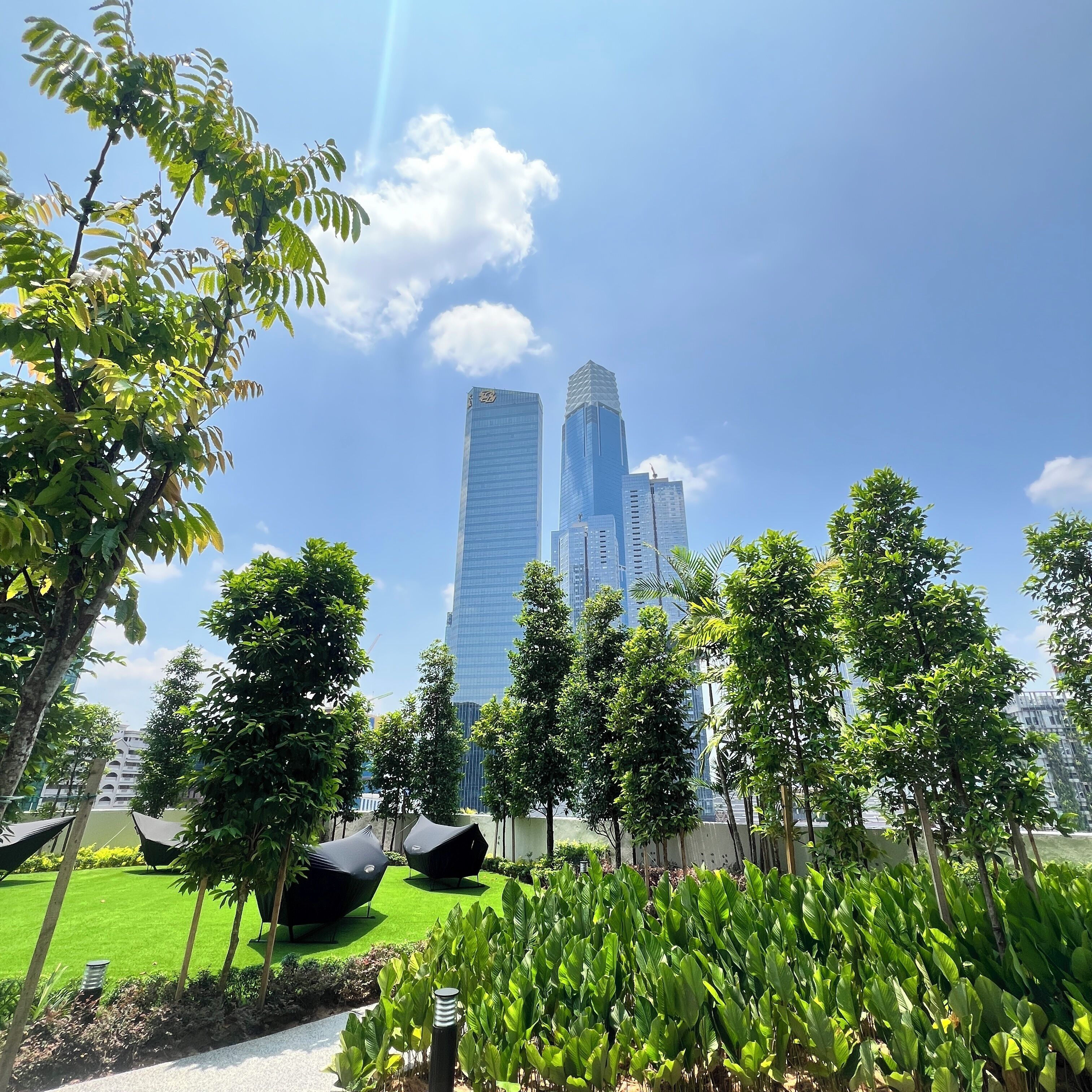 A modern building with a unique geometric design, surrounded by lush greenery and a well-maintained lawn.