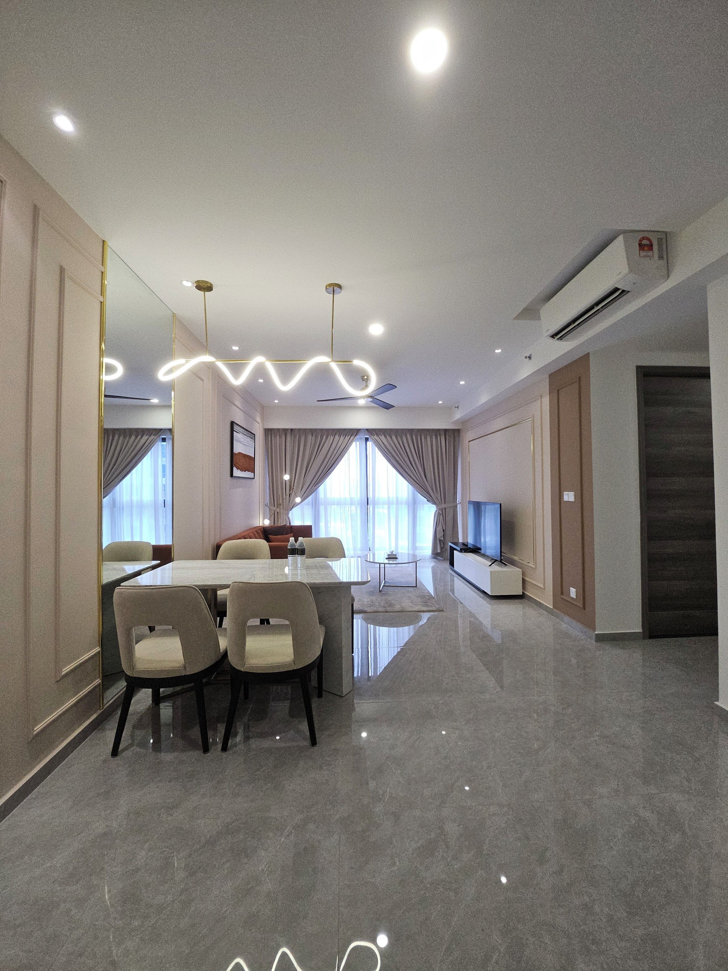 A modern hotel room with a dining area, a TV, and a large window with curtains.