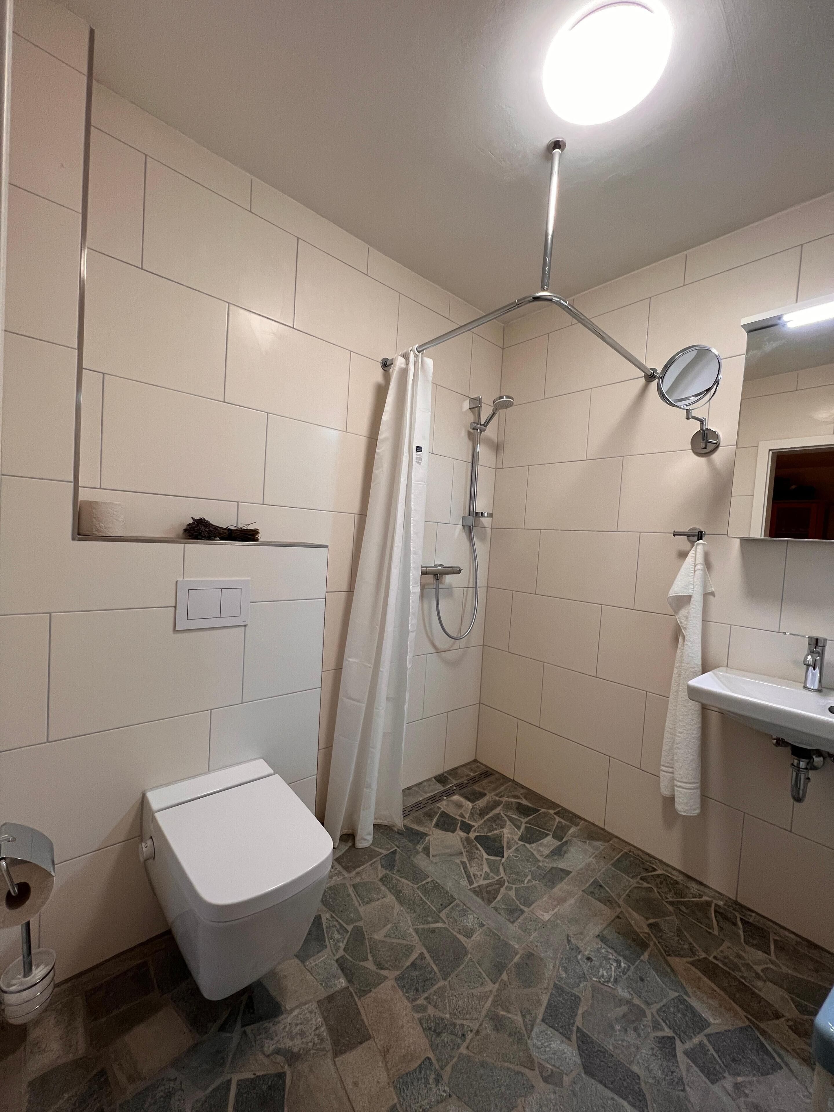 A bathroom with a toilet, shower, and sink.