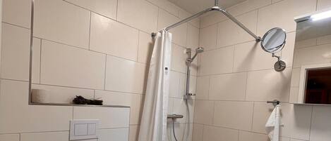 A bathroom with a toilet, shower, and sink.