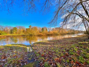 A river with a stone path leading to it, surrounded by trees and grass. - Ferienhaus, 90m², 1-8 Pers (Rheine)