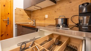 A modern kitchen with wooden cabinetry, a stainless steel countertop, a coffee maker, and a built-in dishwasher. - Steil Alva Studios Smit by Interhome (Lenzerheide)