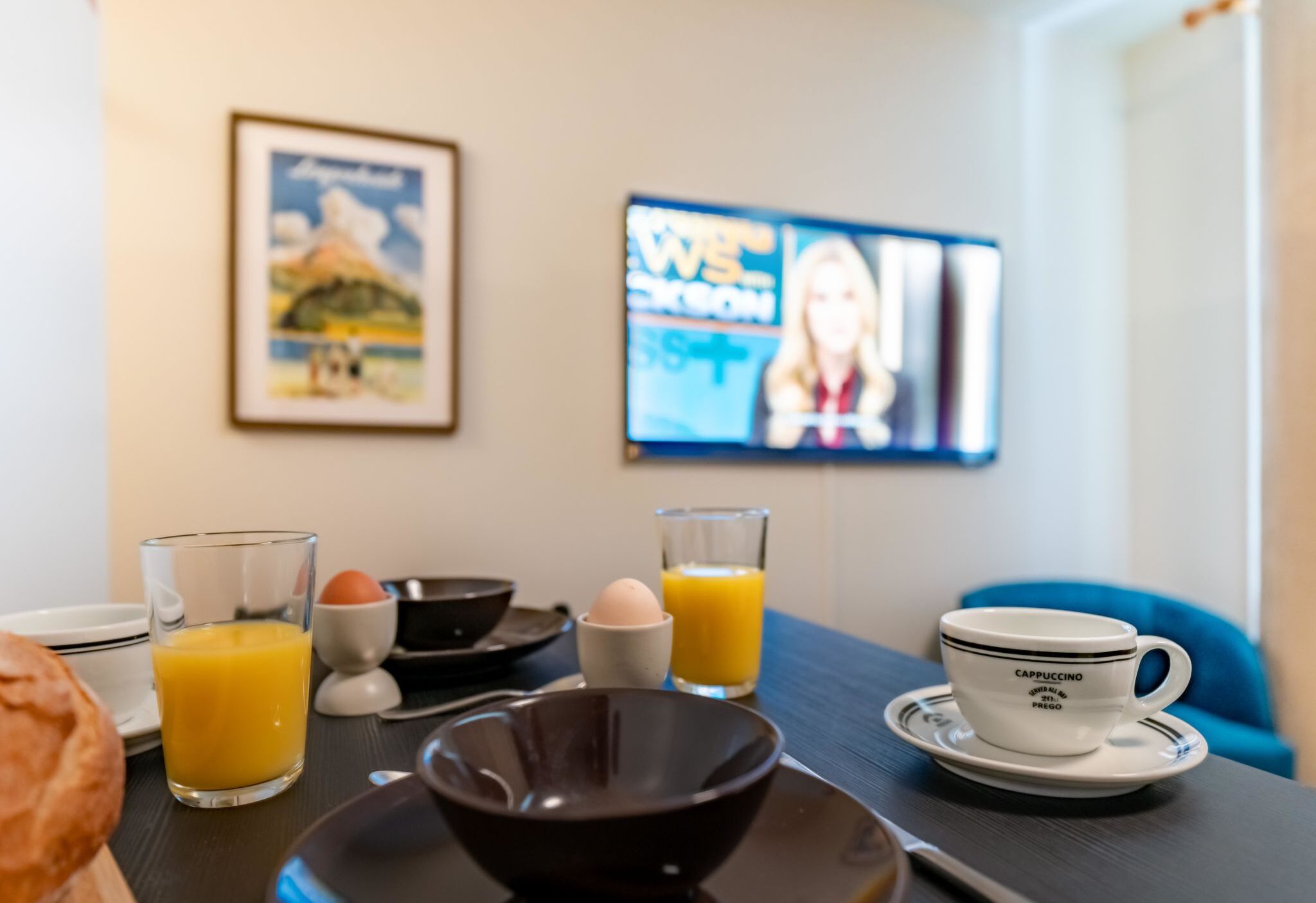 Un desayuno servido con una taza de café, jugo de naranja y un bol sobre una mesa.