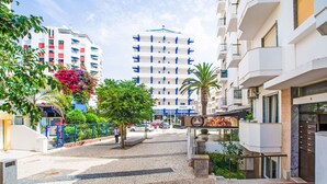 A hotel entrance with a cobblestone pathway leading to a gated entrance, surrounded by modern buildings and greenery. - Seaside Getaways by Interhome (Armação de Pêra)