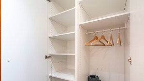 A white closet with wooden hangers and a black storage tube. - Steil Alva Studios Smit by Interhome (Lenzerheide)