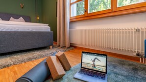 A bedroom with a bed, a laptop on a yoga mat, and a window with a view of trees. - Steil Alva Studios Smit by Interhome (Lenzerheide)