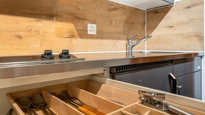 A modern kitchen with wooden cabinetry, stainless steel appliances, and a built-in dishwasher. - Steil Alva Studios Smit by Interhome (Lenzerheide)