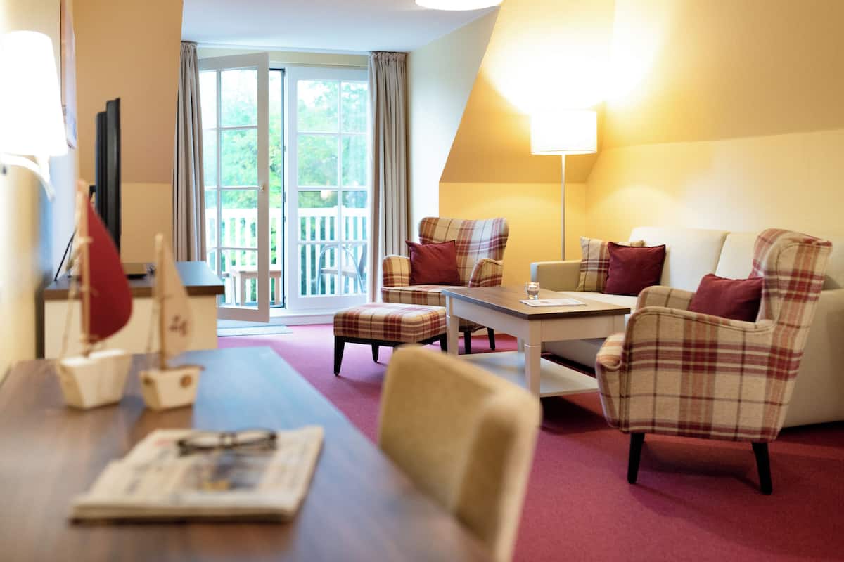 Ein Zimmer mit Esstisch, zwei Stühlen, einer Couch und einer Lampe.