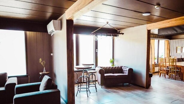 A spacious living area with a sofa, chairs, a small table, and a hanging light fixture. - VOSSESTØLEN HOTEL (Voss)