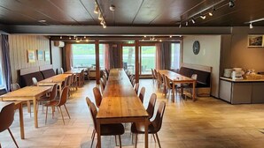 A spacious dining area with long wooden tables and chairs, large windows, and a view of the outdoors. - VOSSESTØLEN HOTEL (Voss)