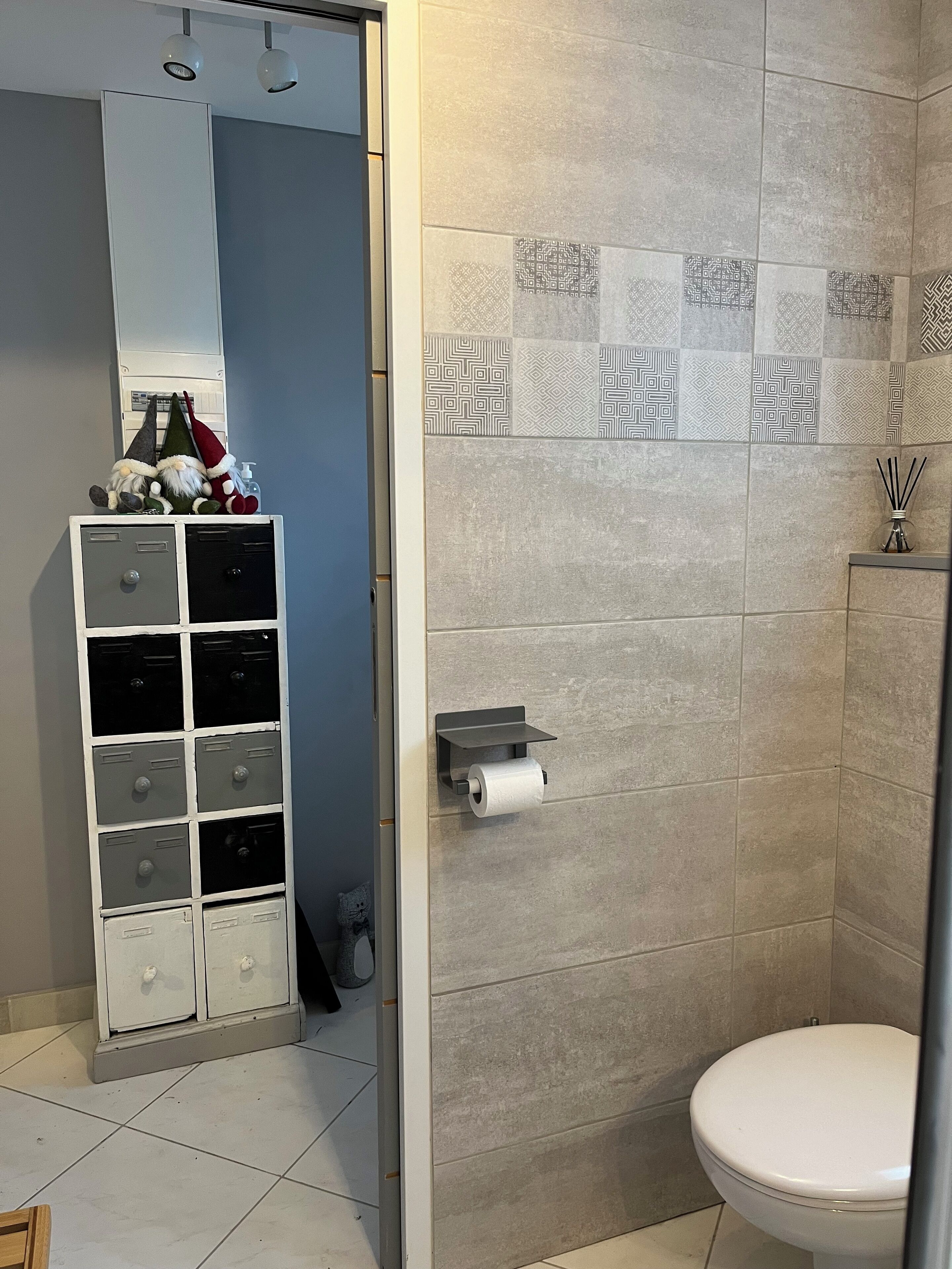 A bathroom with a toilet, a towel rack, and a storage unit with multiple drawers.