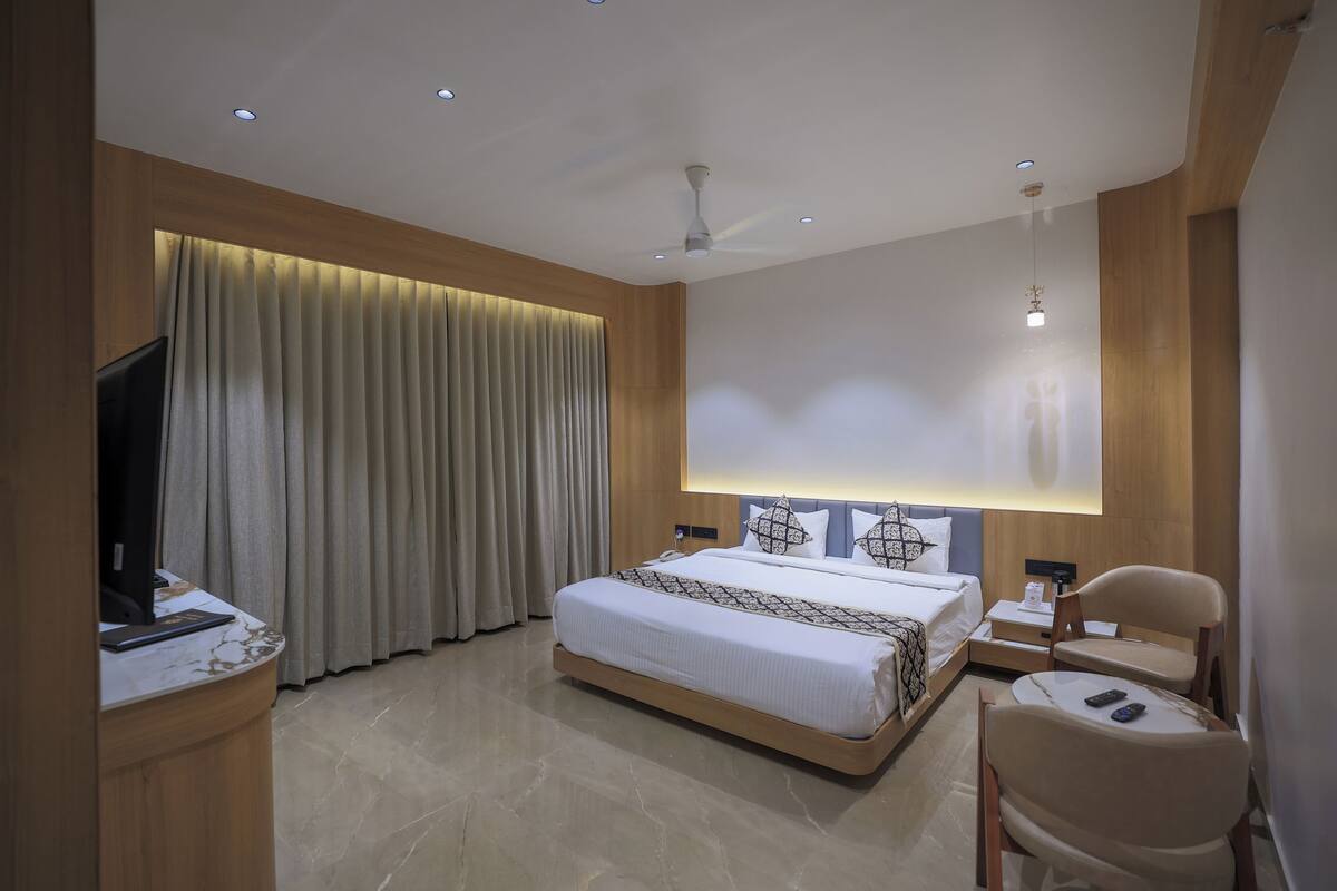 Une chambre d’hôtel moderne équipée d’un grand lit, d’un bureau avec un ordinateur, d’une chaise et d’un ventilateur de plafond.