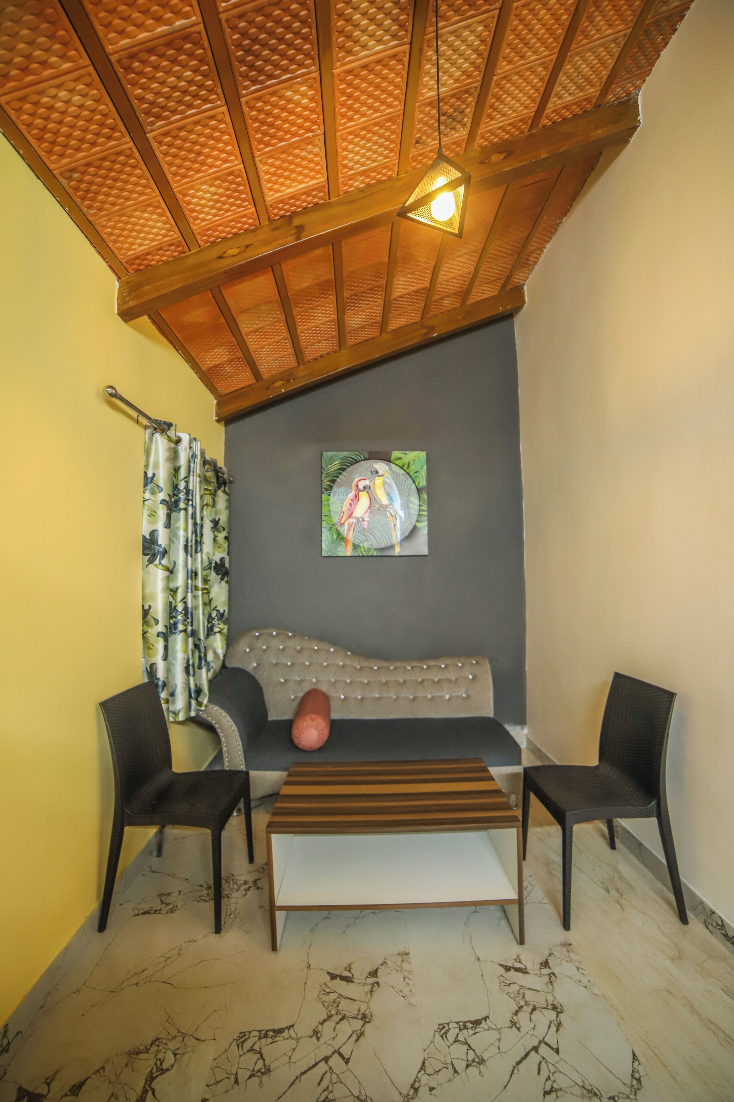 Habitació d'alt sostre, un sofà, dues cadires, un quadre i una cortina.