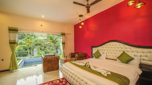 A bedroom with a large bed, a ceiling fan, and a view of a pool and greenery. - Rain Rock Villa (Yercaud)