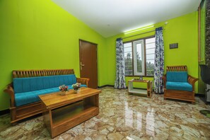 A living room with a sofa, a wooden coffee table, and two armchairs. - Rain Rock Villa (Yercaud)