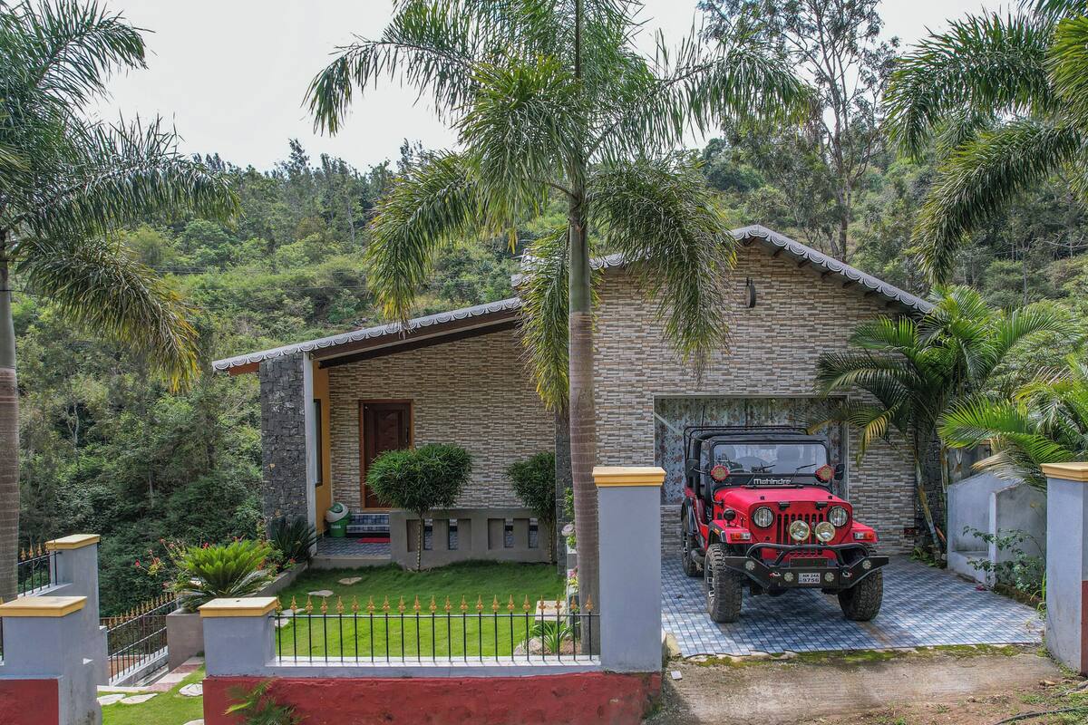 A stone house with a red jeep parked in front.