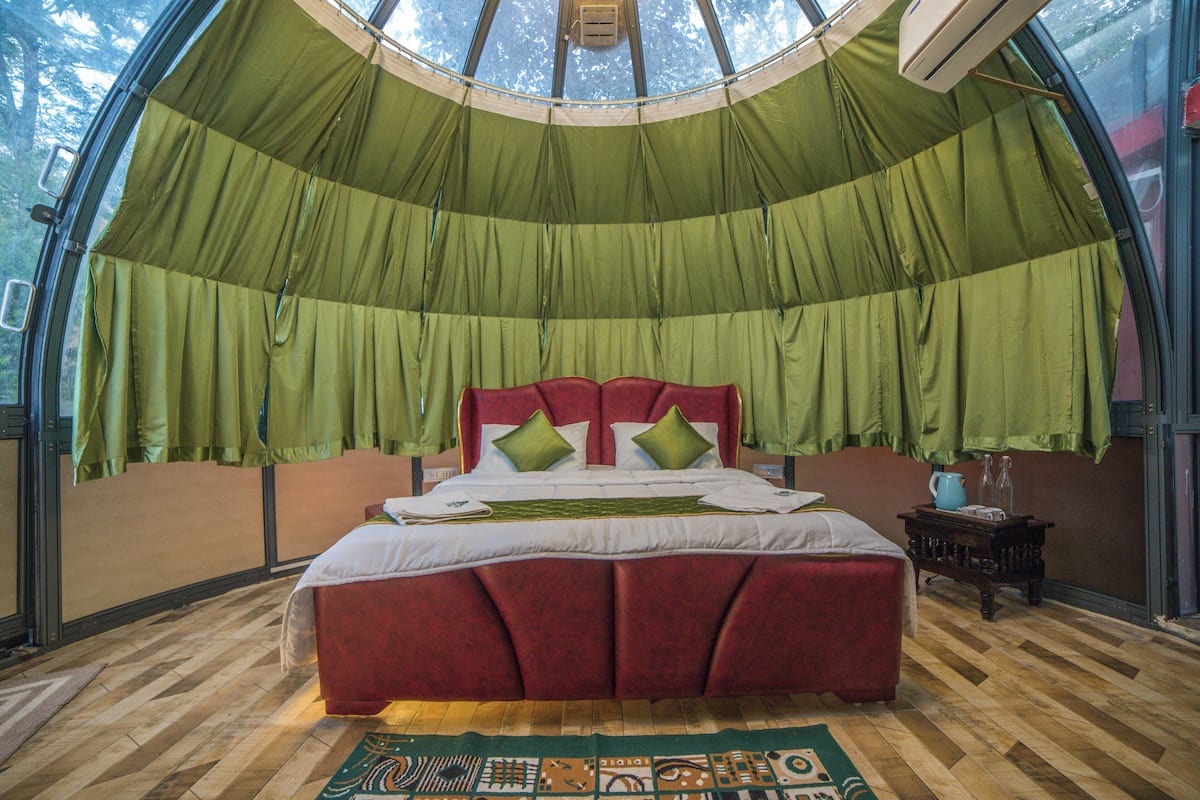 Ein Zimmer mit einem großen Bett, grünen Vorhängen und Holzboden.