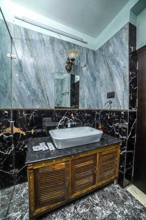 A bathroom with a marble wall, a sink, and a wooden cabinet. - Rain Rock Villa (Yercaud)