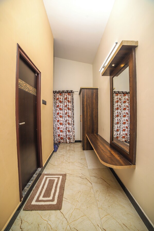 A hallway with a wooden door, a bench, a mirror, and a patterned curtain. - Rain Rock Villa (Yercaud)