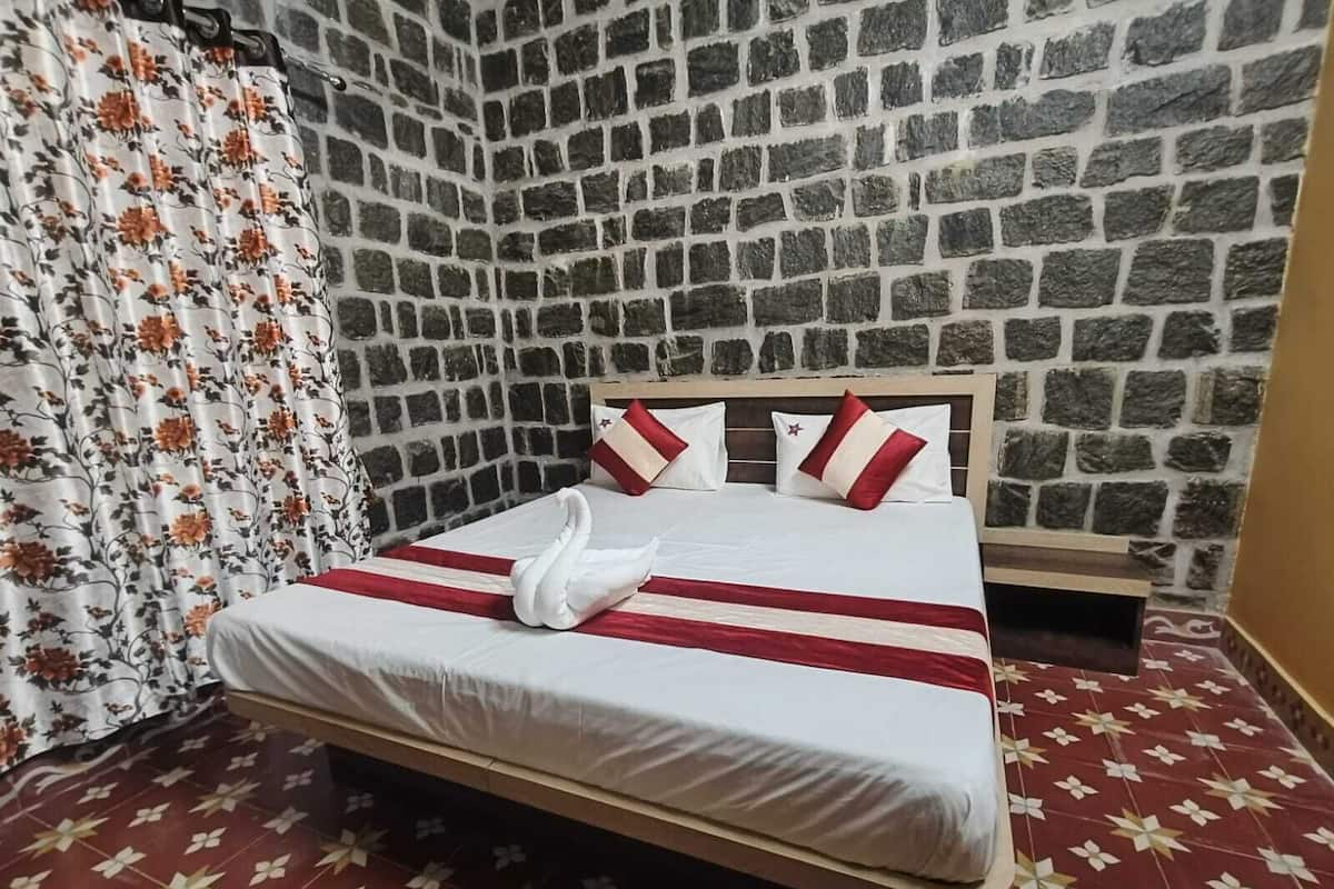 Ein Bett mit einer Schwanen-Pillow, rot-weiß gestreifter Bettwäsche und einem floralen Vorhang.