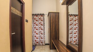 A hallway with a wooden door, a mirror, a bench, and patterned curtains. - Rain Rock Villa (Yercaud)