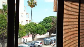 Guests can enjoy a view of the street lined with trees and a palm tree from the comfort of their room.