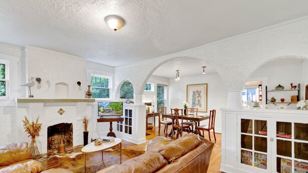 A spacious living room with a fireplace, leather sofa, dining table, and white cabinets. - Historic Spanish Charm + Scenic View | Cozy Casita (Birmingham)