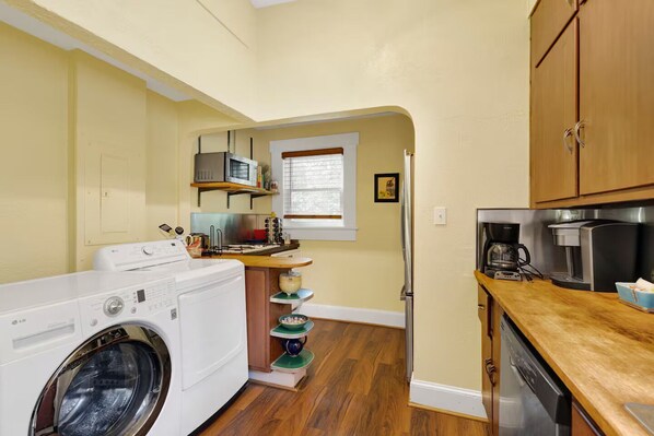 A compact kitchen with a washing machine, microwave, and coffee maker. - Historic Spanish Charm + Scenic View | Cozy Casita (Birmingham)