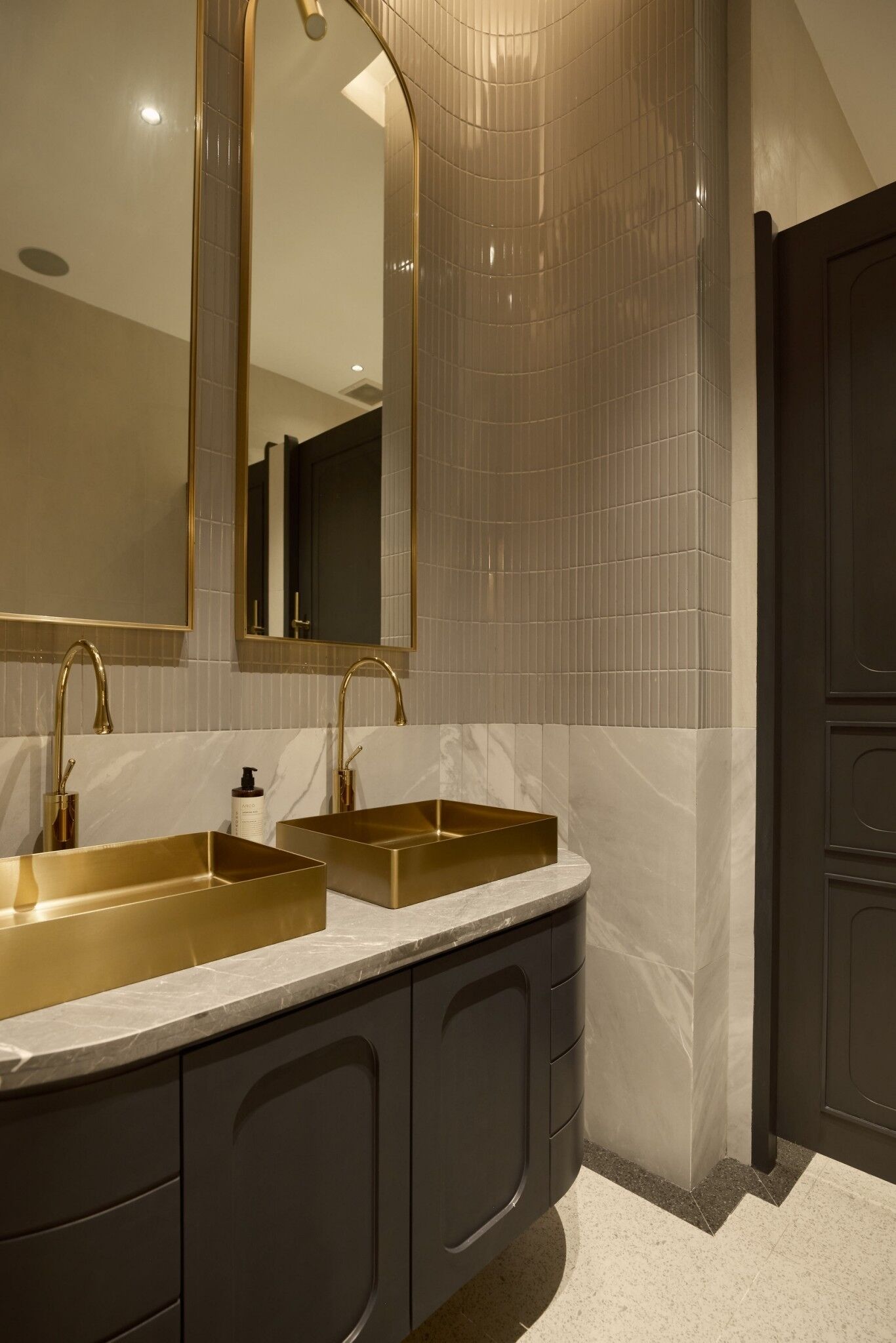 Ein modernes Badezimmer mit zwei goldenen Waschbecken, dunklen Schränken und einem großen Spiegel.