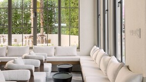 Een moderne lounge met een lange bank, meerdere sofa's en ronde salontafels.