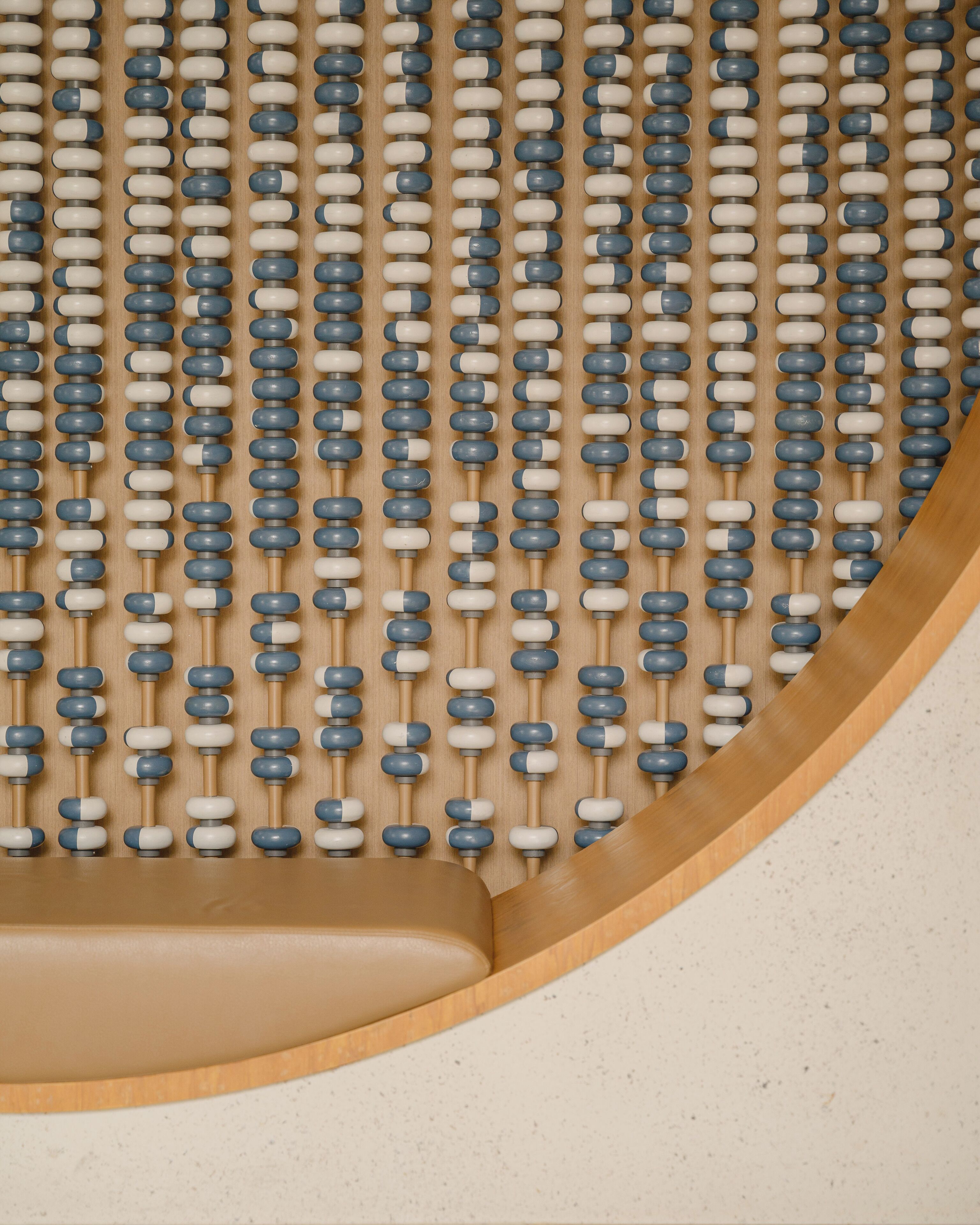 A close-up of a wooden slat wall with evenly spaced, cylindrical beads.