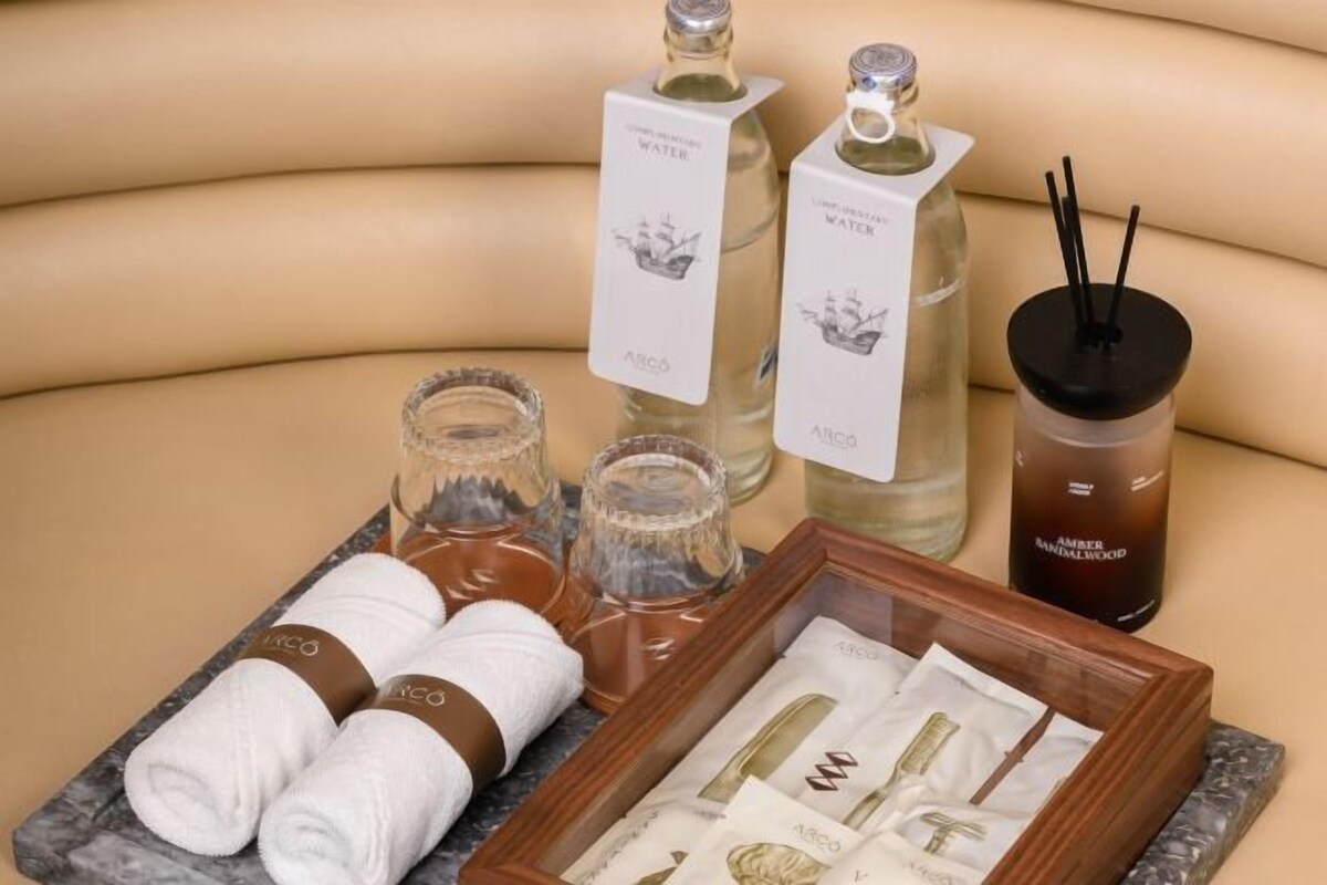 A spa setting with bottles of water, a bottle of amber wood oil, and towels on a marble surface.