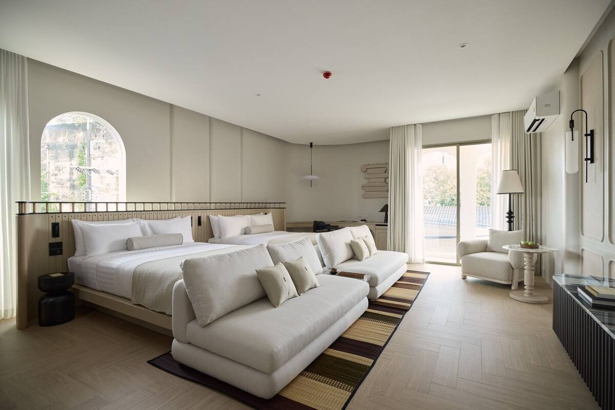 Une chambre d’hôtel moderne, dotée d’un grand lit, d’un canapé, d’une petite table et offrant une vue sur l’extérieur.