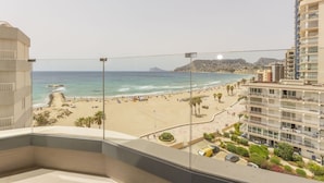 A balcony with a view of a beach, a parking area, and a building with multiple floors. - Apartamento Infinium 3 - Costa CarpeDiem (Calpe)