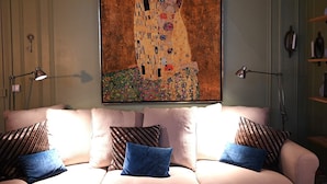 A living room with a large Gustav Klimt painting, a beige sofa with patterned cushions, and two floor lamps. - Olympic Games 2024 : Direct to Stade de France (Paris)