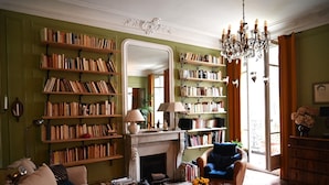 A cozy living room with a fireplace, bookshelves, a sofa, and a chandelier. - Olympic Games 2024 : Direct to Stade de France (Paris)