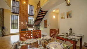 A dining area with a wooden table set for four, a staircase, and a brick wall. - Rock Villa  (Ootacamund)