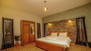 A bedroom with a wooden bed, a wardrobe, a potted plant, and a stone wall. - Rock Villa  (Ootacamund)