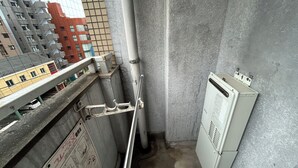 Un couloir étroit avec une rambarde métallique, un compteur et une boîte de raccordement.