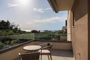 A balcony with a table and chairs, offering a view of the surrounding landscape and buildings. - HP Family Suites (Sithonia)