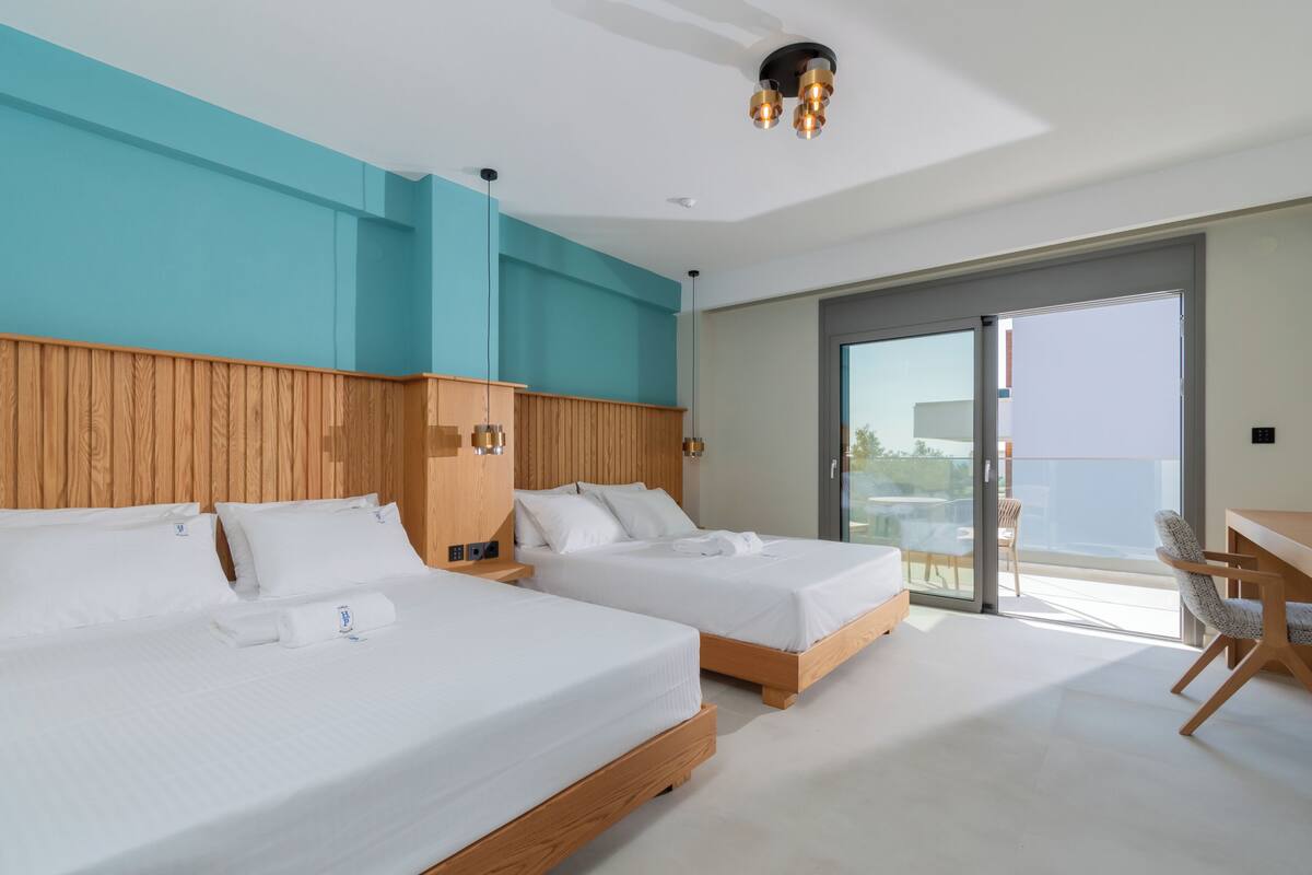 A modern hotel room with two beds, a wooden headboard, a balcony with a view, and a desk with a chair.