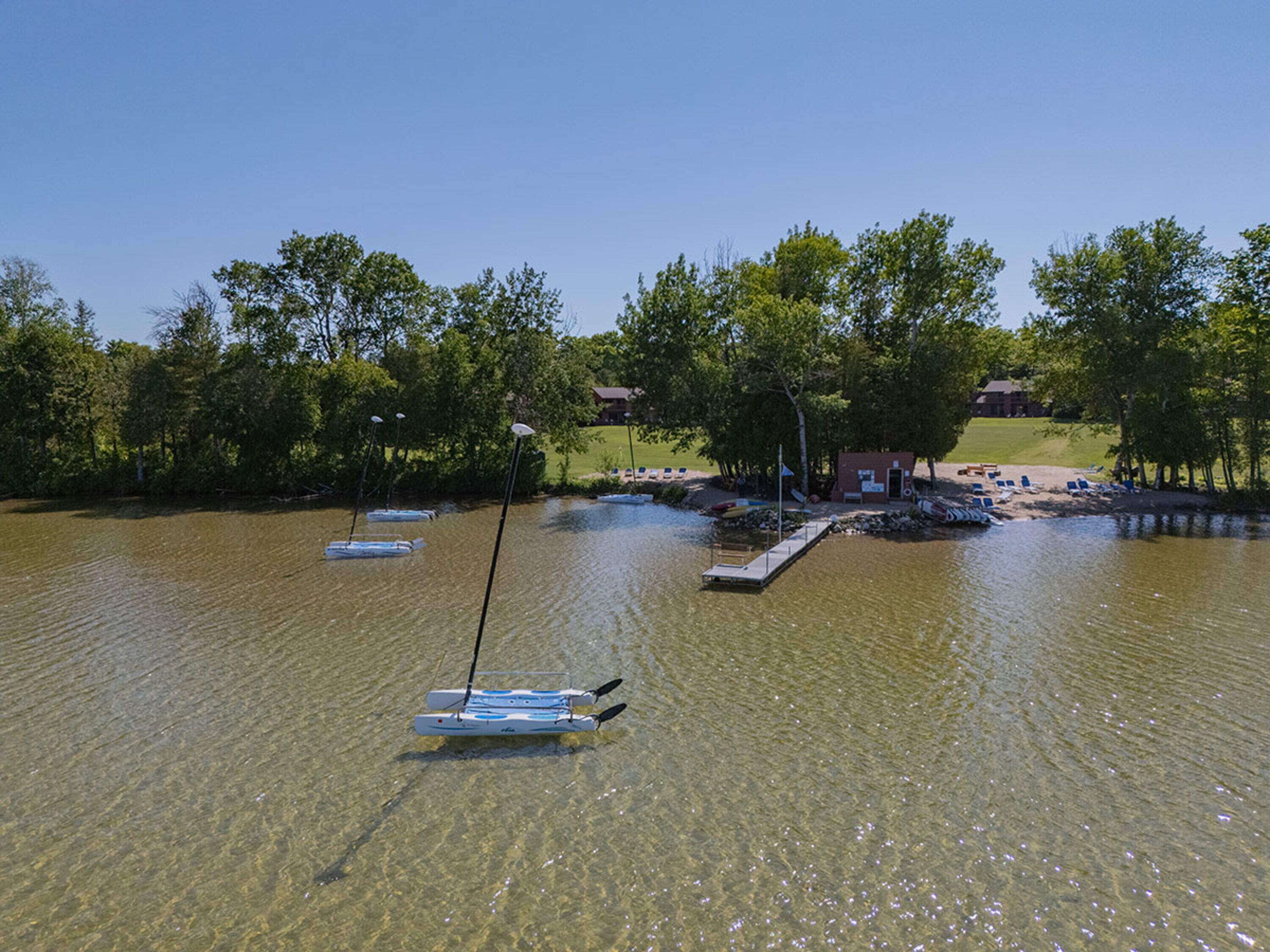 A lakeside area with a dock, boats, and a small building.