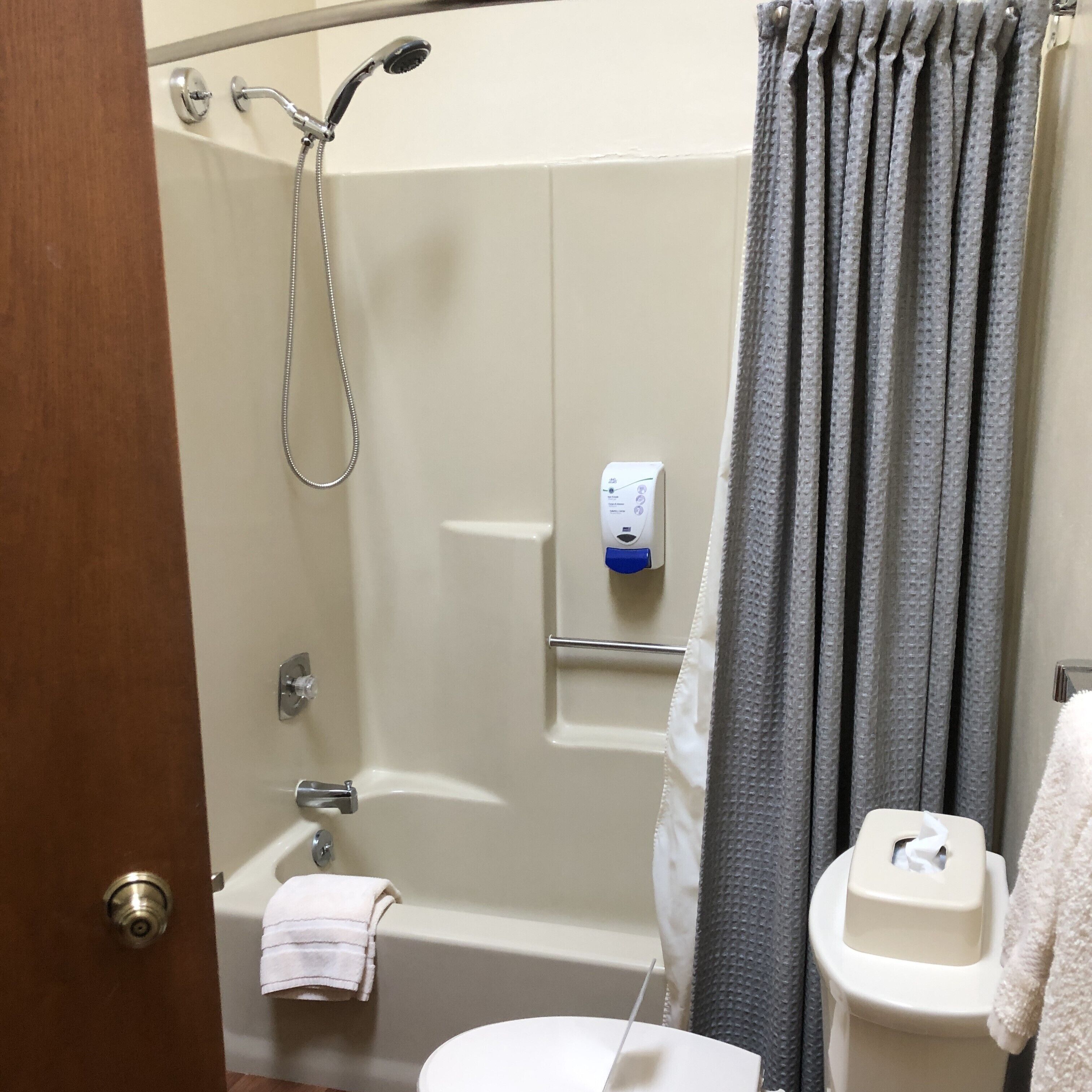 Un baño con ducha, inodoro y toallero.