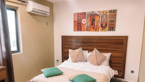 A neatly made bed with a wooden headboard, two green pillows, and a beige bedspread.