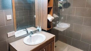 A modern bathroom with a large mirror, a sink, and a shower.