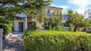 A two-story building with a blue roof, surrounded by well-maintained greenery and a stone pathway leading to the entrance. - Pet friendly apartment in Rab with WiFi (Rab)
