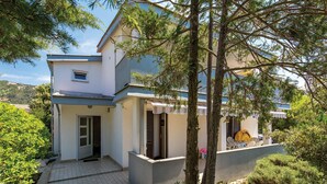 A two-story house with a tiled patio, a covered outdoor seating area, and a view of the surrounding greenery. - Pet friendly apartment in Rab with WiFi (Rab)