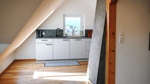 A modern kitchen with white cabinets, a black countertop, and a window with a view of trees. - LakeviewOasis: Exclusive Schnepfhalde apartment (Schluchsee)